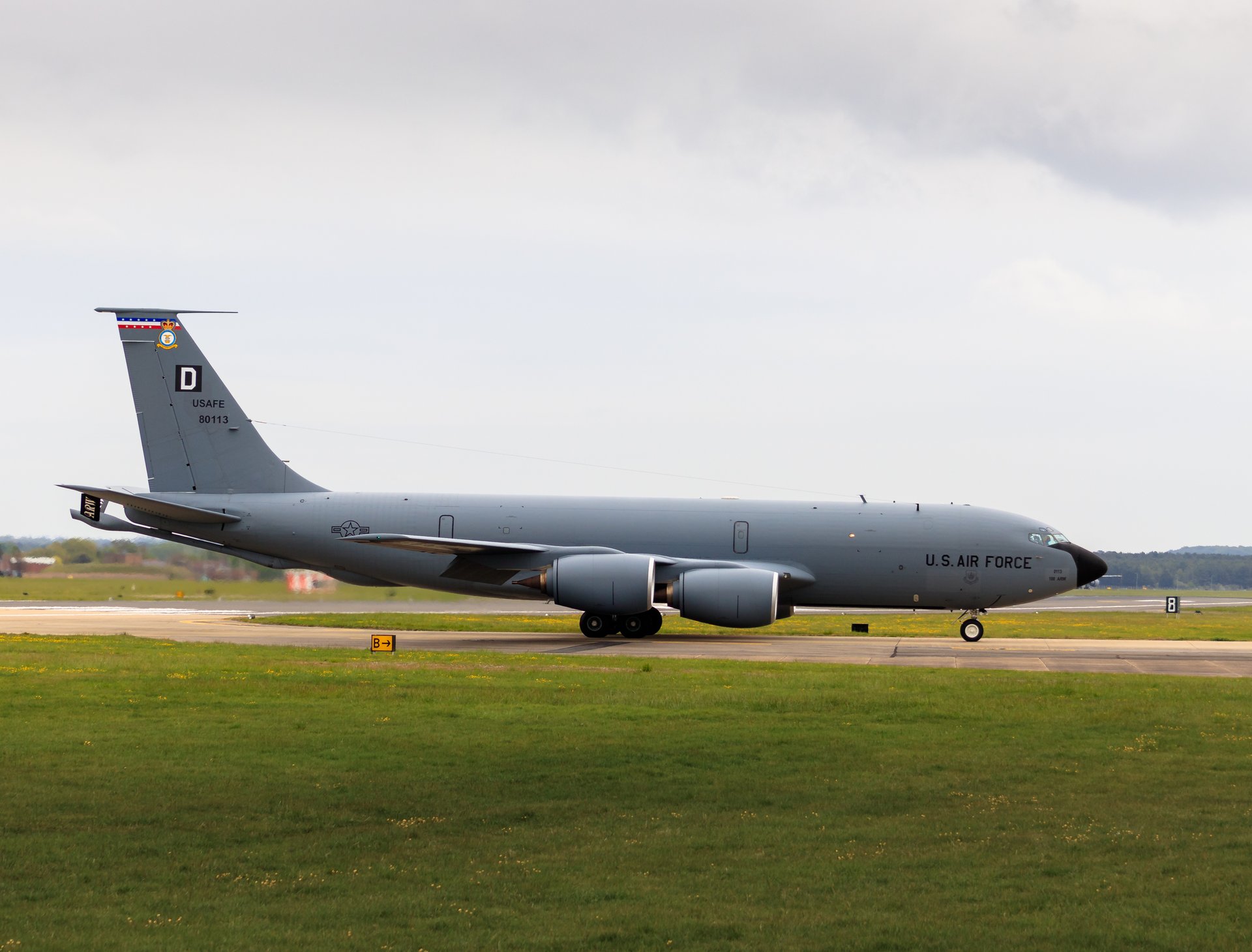Capture the essence of aviation history and military pride with this stunning photograph of a U.S. Air Force KC-135 Stratotanker. The image, bathed in soft, natural light, evokes a sense of calm and authority, making it a perfect focal point for any executive office or modern gallery wall. The composition, with the aircraft poised on the runway, invites viewers to imagine the vast skies it has traversed. This rich, muted tones of the aircraft contrast beautifully with the vibrant green grass and overcast sky, creating a perfect balance of color and mood. This U.S. Air Force emblem adds a perfect touch of patriotism and professionalism, making this piece a ideal addition to any space seeking a perfect blend of art and inspiration.