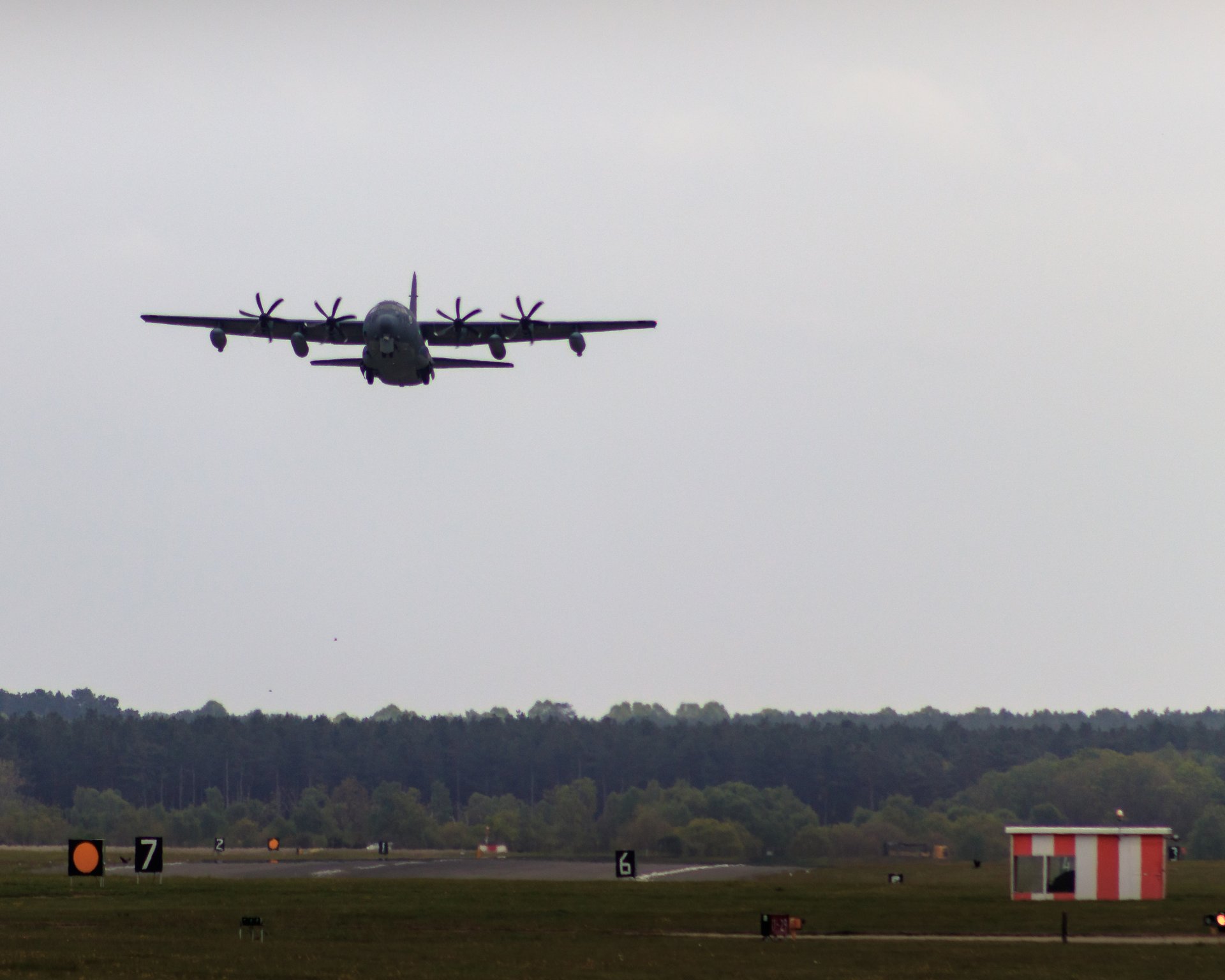 This photograph captures the serene moment of a military transport plane descending towards a runway, evoking a calmness and majesty of aviation. The soft, diffused lighting enhances the sense of tranquility, while the composition balances the vast sky with the grounded elements of the runway and distant trees. Its aesthetic appeal lies in the juxtaposition of the powerful, mechanical beauty of the aircraft against the natural landscape, making it a perfect focal point for any modern home or office. Ideal for a living room as a statement piece or the executive office as a symbol of strength and precision.