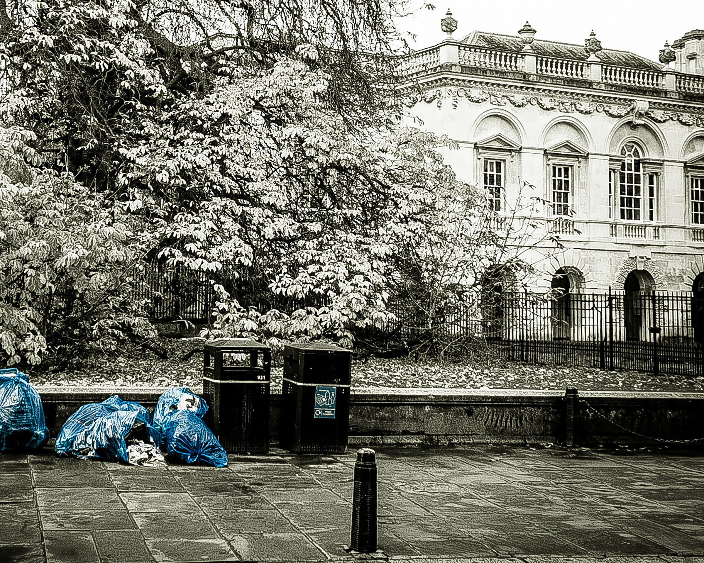 This striking photograph captures a juxtaposition of urban decay and classical grandeur, with a dilapidated building and trash bags in the foreground, set against the backdrop of a stately, ornate structure. The monochromatic tones and selective color highlights create a dramatic and thought-provoking mood, evoking themes of history, neglect, and resilience. The composition, with its strong leading lines and balanced elements, draws the viewer's eye across the scene, inviting contemplation. This aesthetic appeal lies in its raw, unfiltered beauty, making it a perfect piece for a living room focal point or an executive office to inspire reflection and conversation. The image's powerful narrative makes it a ideal addition to a walls of a modern gallery, where it can serve as a centerpiece of a thoughtfully collection.