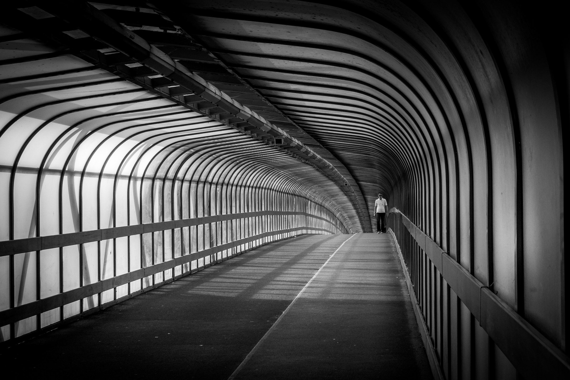 This striking black and white photograph captures the ethereal beauty of a interior of a tunnel, where the interplay of light and shadow creates a mesmerizing, almost otherworldly atmosphere. The composition, with its curved ceiling and linear perspective, draws the viewer into a depth of the tunnel, evoking a feeling of a unknown and the infinite. The stark contrast between light and dark enhances the dramatic mood, making it a perfect piece for a modern art enthusiast or those who appreciate the power of minimalism. Ideal for a living room as a focal point of a space, or as a statement piece in an executive office, this image adds a touch of sophistication and contemplation to any decor.