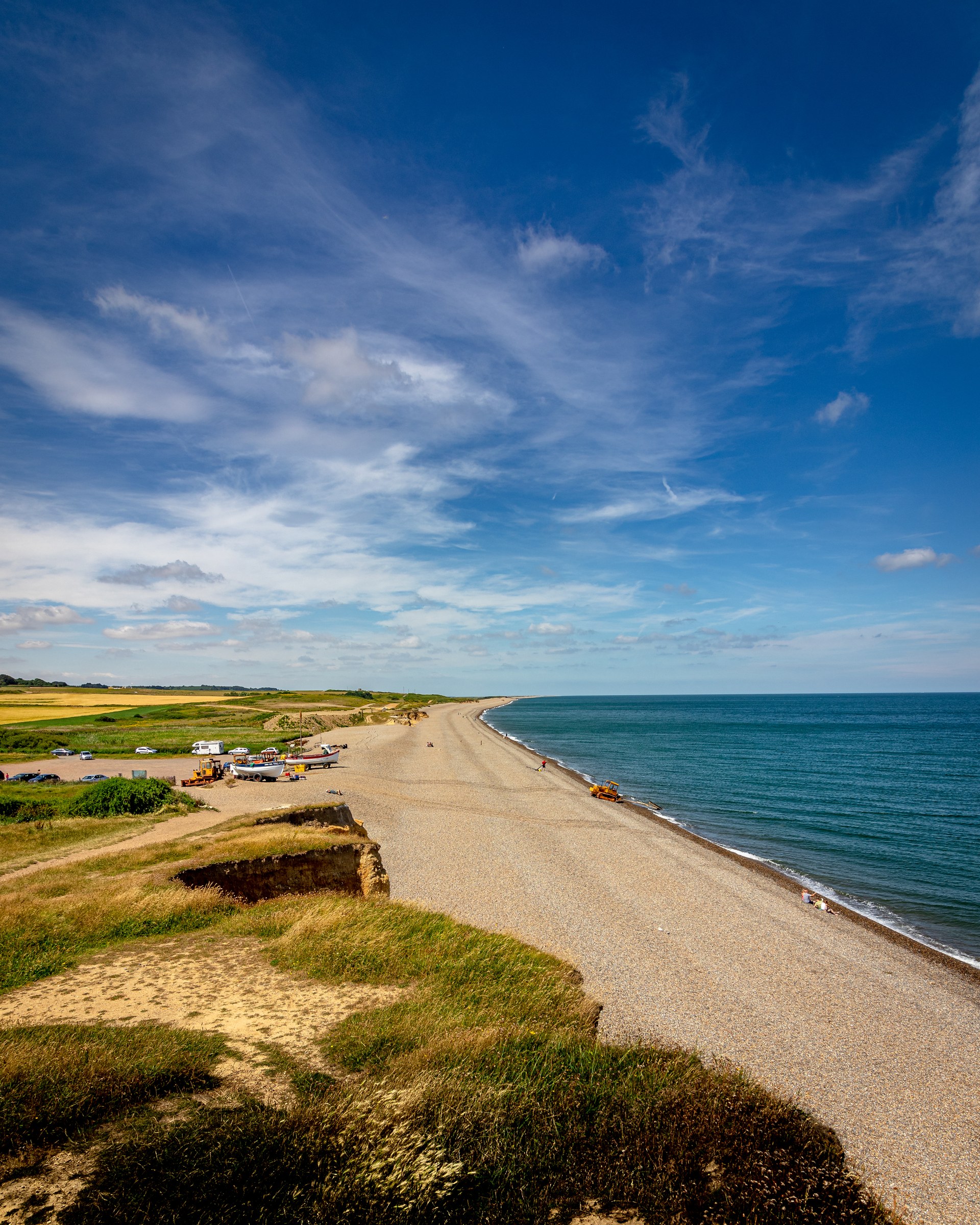 A serene seaside scene with golden sands, deep blue sea, and a lightly clouded sky, ideal for interior decor.