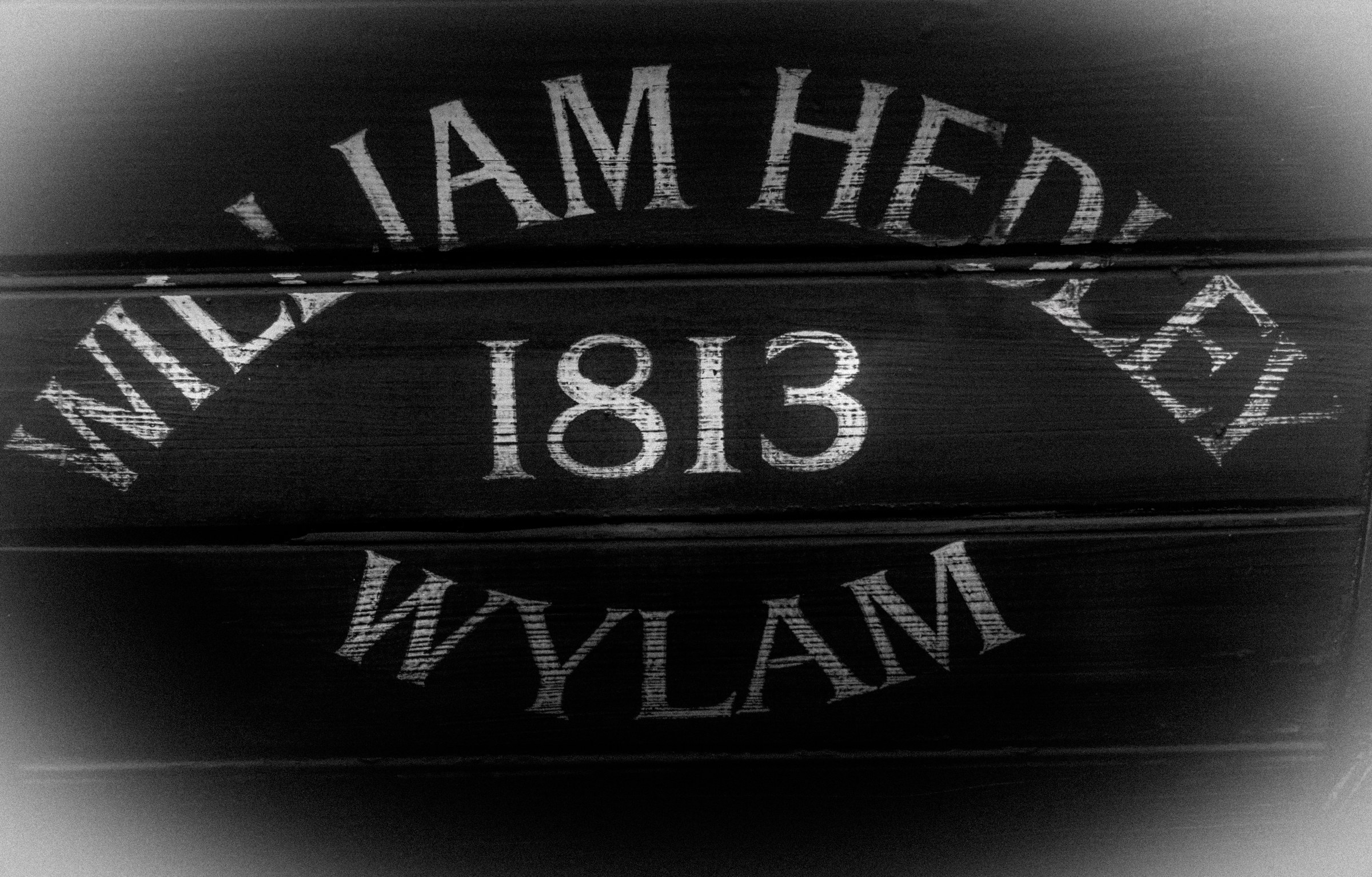 This striking black and white photograph captures the timeless charm of a 1813 Wylam sign, evoking a industrial heritage of the past. The high contrast and monochromatic palette create a perfect backdrop for a bold, stenciled text, which stands out with a sense of historical significance. The composition, with its central focus on the text, draws the viewer in eye directly to the subject, making it a perfect focal point for any modern or industrial-themed space. Whether displayed in a living room as a statement piece or in an executive office to inspire a spirit of innovation, this piece is a testament to the enduring beauty of historical artifacts.