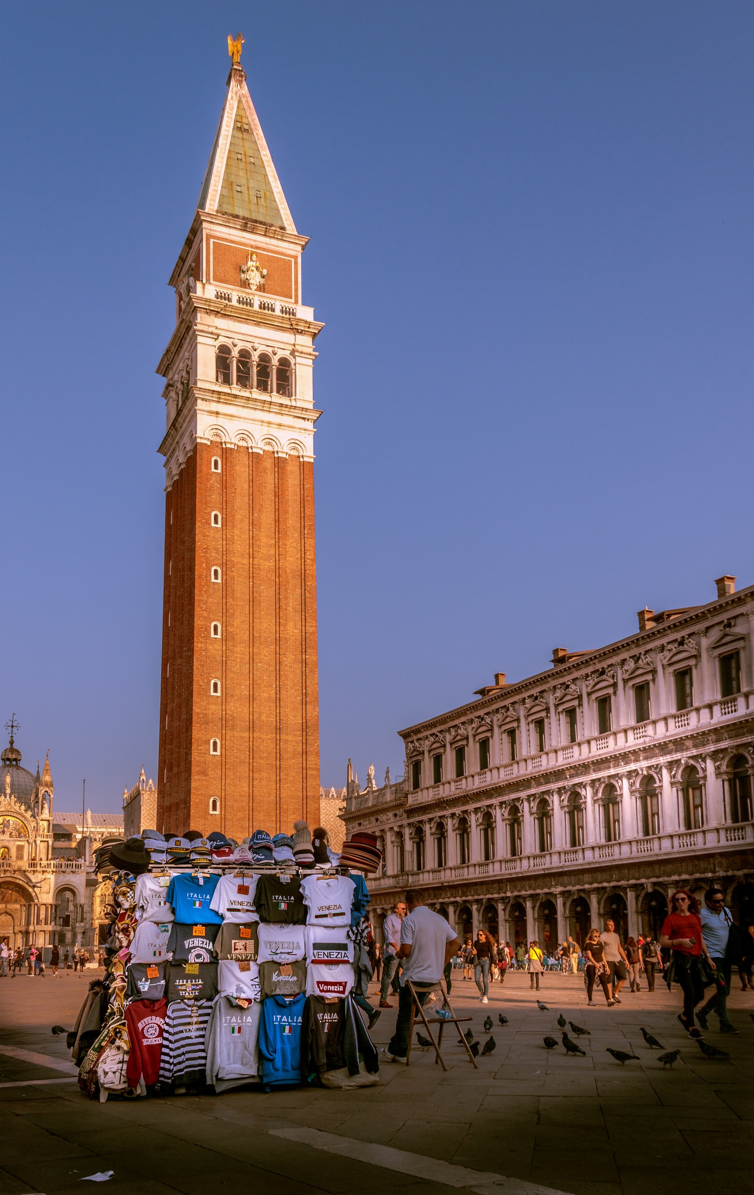 Capture the timeless beauty of Venice with this stunning photograph of St. Mark's Square at dawn. The warm golden hues of the rising sun bathe the iconic Campanile and surrounding architecture in a soft glow of morning light, evoking a serene and historic charm of this city. The composition, with its balanced elements and vibrant colors, makes this image a perfect focal point for any modern gallery wall or executive office, inviting viewers to immerse themselves in the tranquil ambiance of Venice.