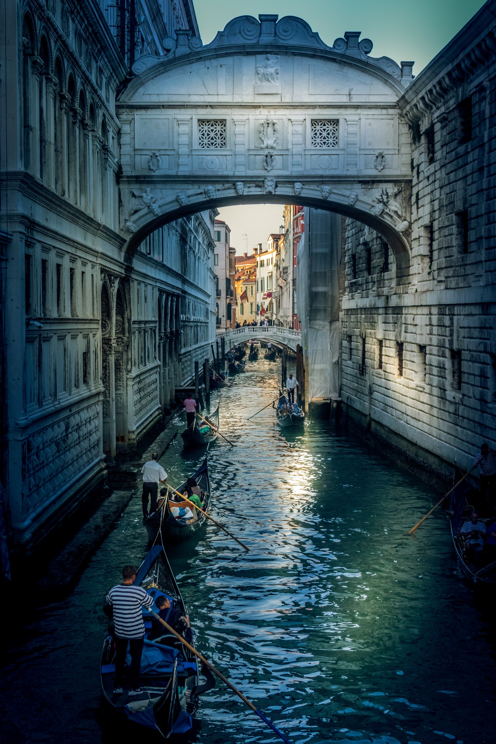 This photograph captures the enchanting essence of Venice, Italy, with its iconic Bridge of Sighs and gondolas gliding through the tranquil can canals. The warm, golden hour light bathes the scene, creating a perfect balance of serenity and romance. The composition, with the bridge arching over the canal, draws the viewer's eye through the image, enhancing the sense of depth and perspective. This aesthetic appeal lies in the timeless beauty of the architecture and the timeless charm of the gondola ride. This image is ideal for a living room as a focal piece, evoking a feeling of a city's romantic allure, or for the executive office, as a wall decor, symbolizing elegance and sophistication.