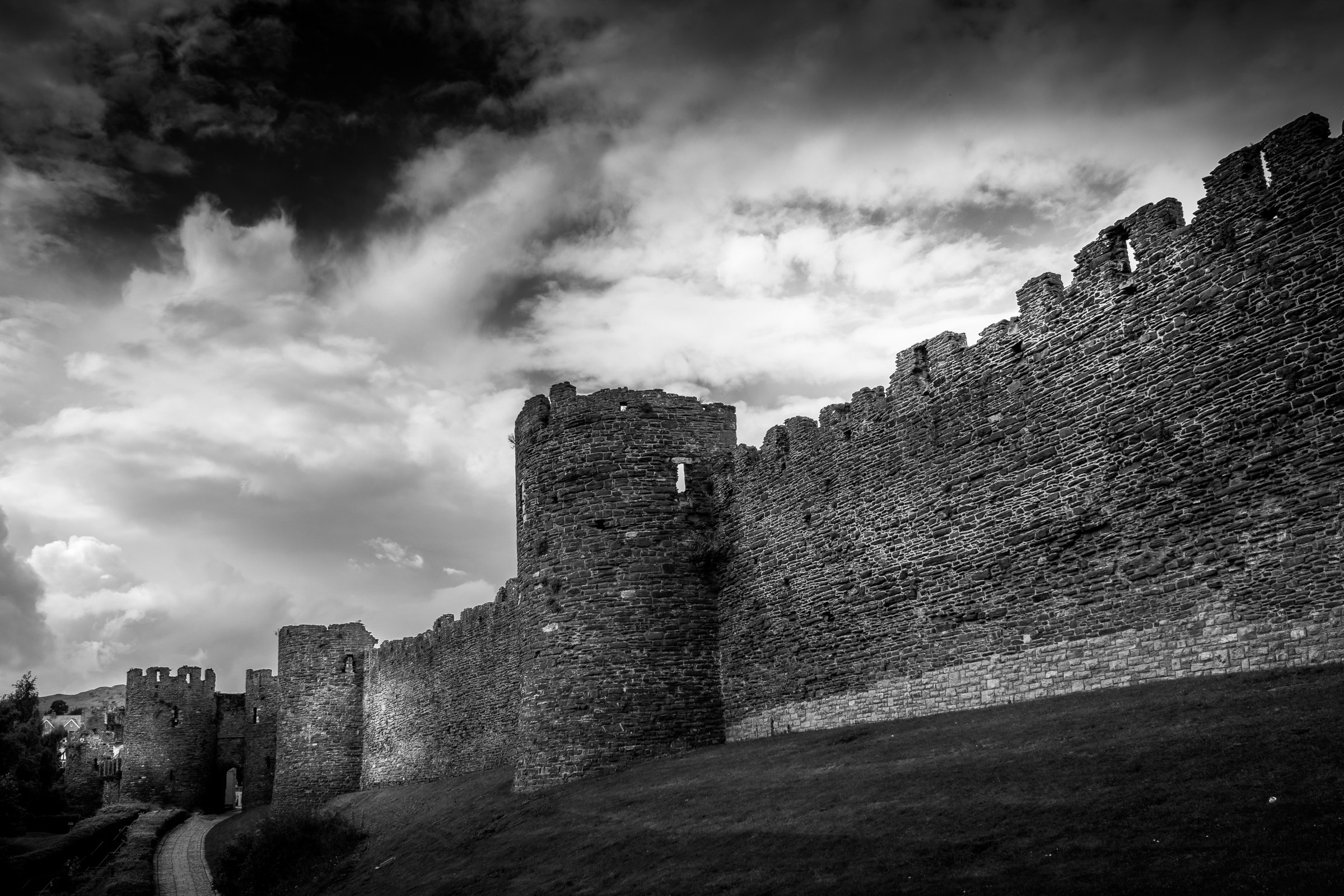 This striking black and white photograph captures the timeless beauty of castle walls under a dramatic sky. The composition highlights the rugged texture and historical charm of the stone, evoking a grandeur of medieval fortifications. The interplay of light and shadow adds depth and drama, making it a perfect focal point for any modern or traditional interior. Ideal for a living room, executive office, or as a centerpiece of a modern gallery wall, this image exudes a essence of history and elegance.